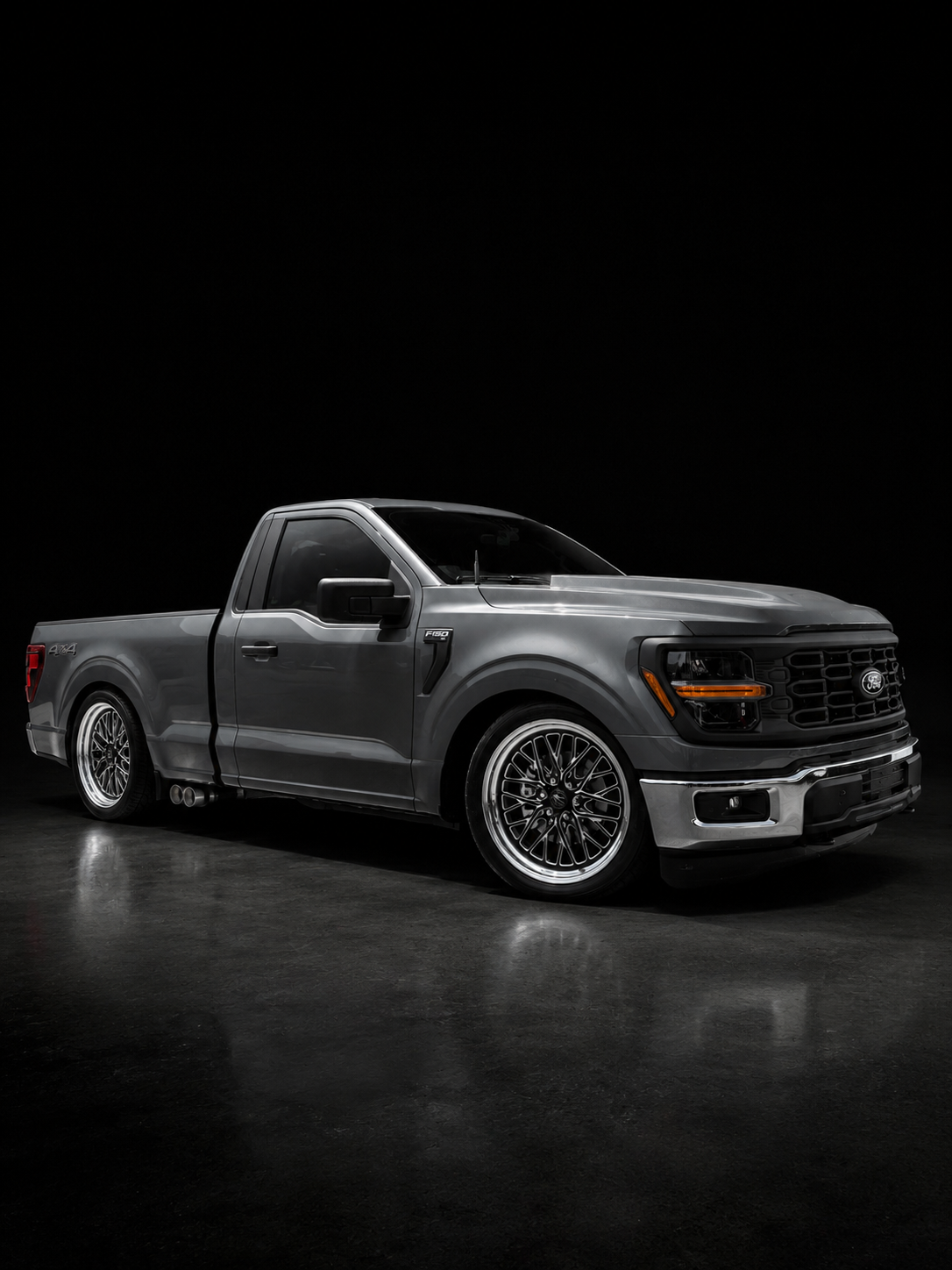 Lowered gray Ford F-150 on a black studio background